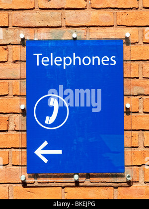 Perspex sign on brick wall showing location of public telephone Stock Photo