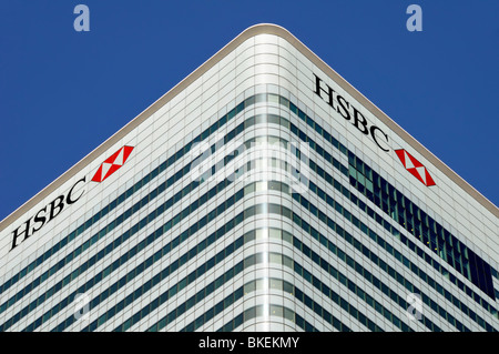 Blue sky corner view of cladding & windows to roof level HSBC bank logo signs at London Docklands Canary Wharf HQ building Tower Hamlets England UK Stock Photo