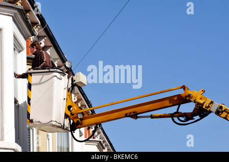 man cleaning house windows from an elevated hydraulic platform Stock Photo