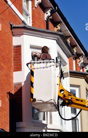 man cleaning house windows from an elevated hydraulic platform Stock Photo