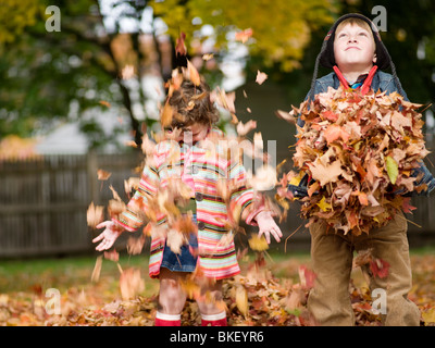 Brother and sister play in autumn park with golden leaves. Baby boy in ...