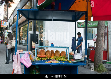 street corner with bright blue fruit vendors cart & pedestrians in Roma district of Mexico City Stock Photo