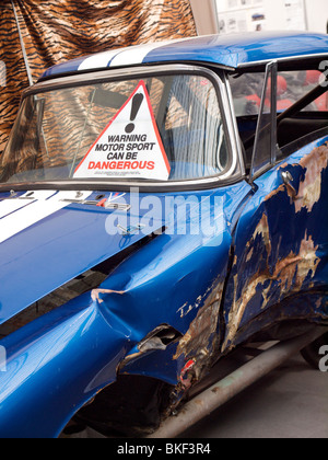 Warning motor sport can be dangerous sign on wrecked Sunbeam Tiger classic sports car Stock Photo