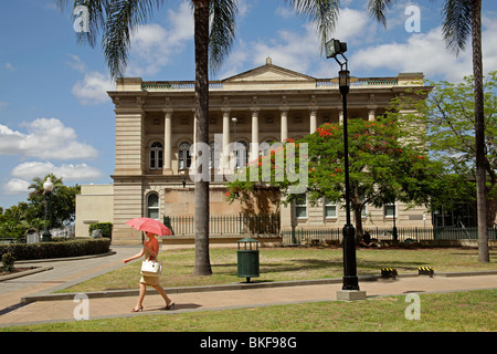 woman with umbrella at Queens Gardens in front of the old State Library Building in Brisbane, Queensland, Australia Stock Photo