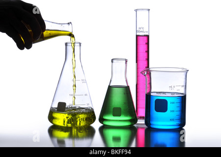 Laboratory Glassware containing different colored liquids against a neutral background Stock Photo