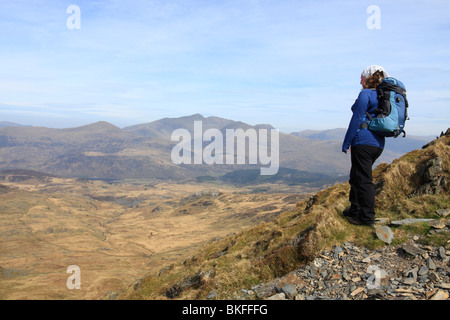A female hill walker looks out to the Snowdon Horseshoe from the slopes of Cnicht in the Moelwyn mountains of Snowdonia, Wales Stock Photo