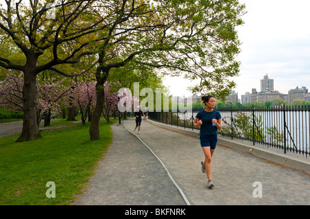 Woman running on the 1.57 mile ( 2.5 k) path that encircles the Jacqueline Kennedy Onassis Reservoir in Central Park Stock Photo