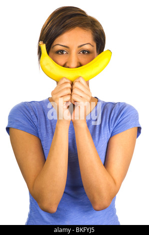 A young woman holds up a banana to her mouth, imitating a smile. Stock Photo