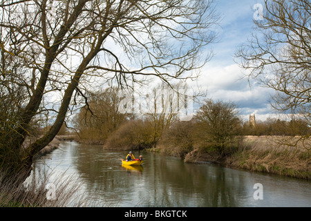 A small boat on the upper reaches of the River Thames in The Cotwolds looking across to St Mary Church in Kempsford, Gloucesters Stock Photo