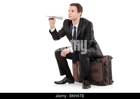 A businessman sitting on a luggage and holding a paper toy plane Stock Photo