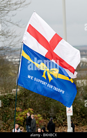st georges flag being held above a we support our troops flag in dudley at an edl rally Stock Photo