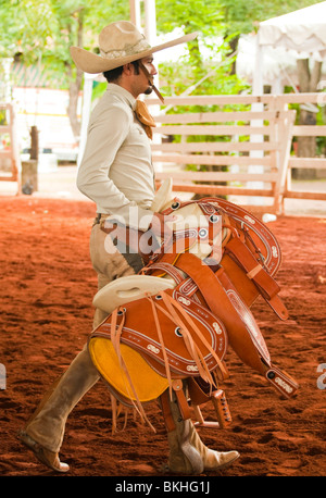 Guadalajara, Mexico, Charro ( Mexican Cowboy) carrying his saddle in horse arena, Club Charro Lienzo, Jalisco Stock Photo