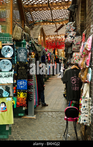 a passageway through clothing, fabric, materials and souvenir market stalls in Camden market North London Stock Photo