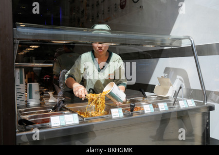 UK SERVING NOODLES AND ORIENTAL FOOD AT A CHINESE TAKE AWAY IN LONDON Stock Photo