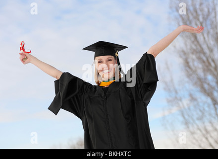 excited attractive graduate with diploma celebrating with arms stretched in the air Stock Photo