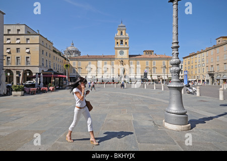 Smart young woman using moblie phone in Piazza Garibaldi public square with the 1760 Palazzo del Governatore and its bell tower Stock Photo