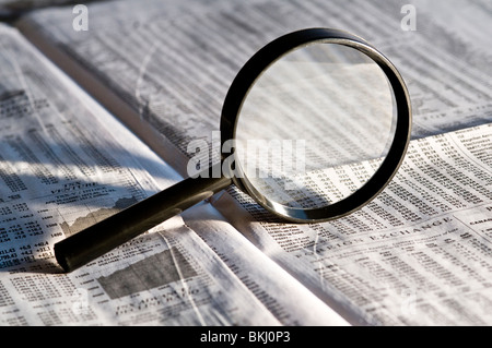 Magnifying glass highlighting stock quotes in business section of financial newspaper. Stock Photo