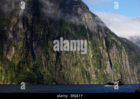 A boat cruises through Milford Sound in the Fiordlands, South Island, New Zealand Stock Photo