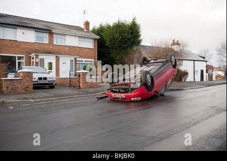 Car crashed overturned on roof after skidding on icy road Elderly driver Stock Photo