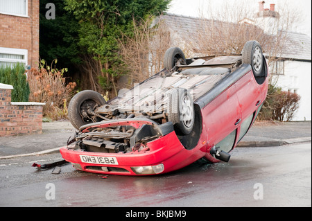 Car crashed overturned on roof after skidding on icy road Stock Photo