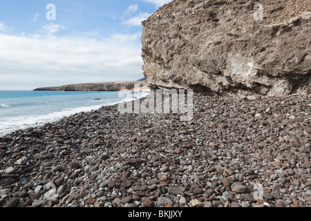 A beach of volcanic rock pebbles near the harbour at Morro del Jable, on the Canary island of Fuerteventura Stock Photo