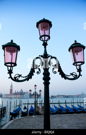 Ornate lamps and gondolas moored at San Marco before dawn in Venice Italy Stock Photo