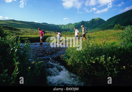 Group of walkers crossing a stream in Auvergne. France. Stock Photo
