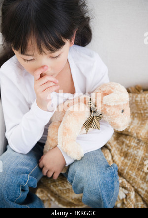 Chinese girl sucking thumb and holding teddy bear Stock Photo