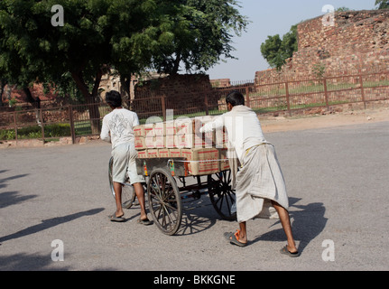 men pulling cart loaded with packs of goods in India together Stock Photo