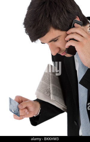 Young businessman holding mobile phone, newspaper and credit card on white background Stock Photo