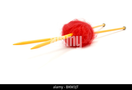 A small ball of red mohair wool pierced with large yellow knitting needles against white. Stock Photo