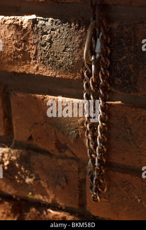 Rusted chain against face brick wall in shaft of sunlight. Long exposure. Stock Photo