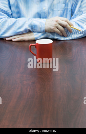 red coffee mug standing in front of man Stock Photo