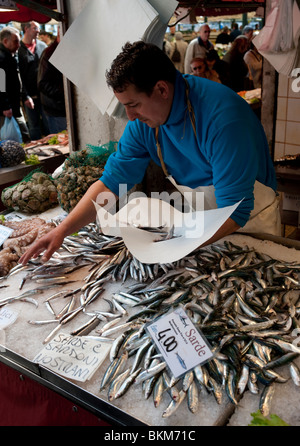 Fishmonger selling sardines at fish market near Rialto Bridge in Venice italy Stock Photo