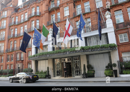 The canopied main entrance and lone doorman at the terracotta colored facade of Claridges Hotel in Brook St Mayfair. Stock Photo