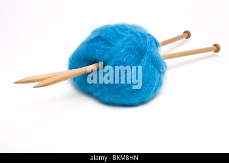 A large ball of blue mohair wool pierced with large wooden knitting needles against white. Stock Photo