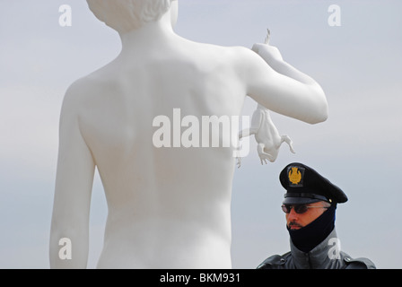 A policeman stands next to Charles Ray's 'Boy With Frog' at the Dogana, Venice, Italy Stock Photo