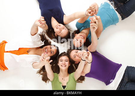 Five teenagers lying on floor in a circle holding hands Stock Photo