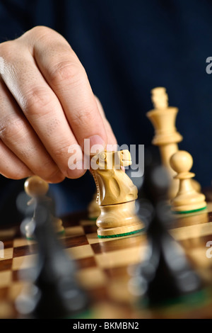 Hand moving a knight chess piece on wooden chessboard Stock Photo