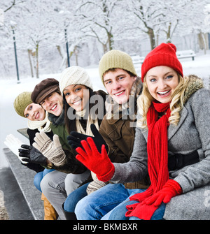 Group of diverse young friends waving hello outdoors in winter Stock Photo