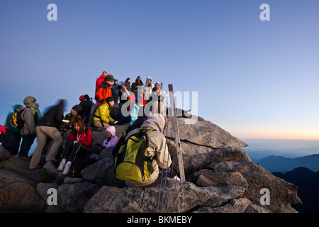 Climbers crowd the summit of Mt Kinabalu at Low's Peak, at dawn. Kinabalu National Park, Sabah, Borneo, Malaysia. Stock Photo