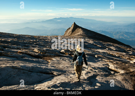 Hiker on Mt Kinabalu with South Peak in the background. Kinabalu National Park, Sabah, Borneo, Malaysia. Stock Photo