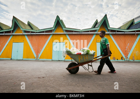 Man pushing wheelbarrow full of produce, in front of the Filipino Handicraft Market. Kota Kinabalu, Sabah, Borneo, Malaysia. Stock Photo