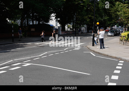 Tourists walking across the famous Abbey Road crossing featured on The Beatles album, Abbey Road outside the recording studios Stock Photo