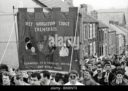 Coal miners and families march through village on last day of work at Deep Navigation Colliery Treharris Glamorgan South Wales Stock Photo