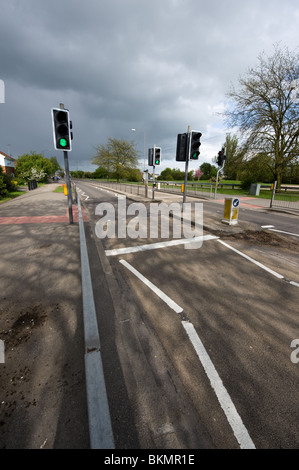 traffic lights under a stormy sky with lights on green for go, pedestrian crossing with traffic island Stock Photo