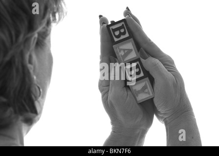 Grandma holding baby. Woman holding children's blocks that spell 'BABY' Stock Photo