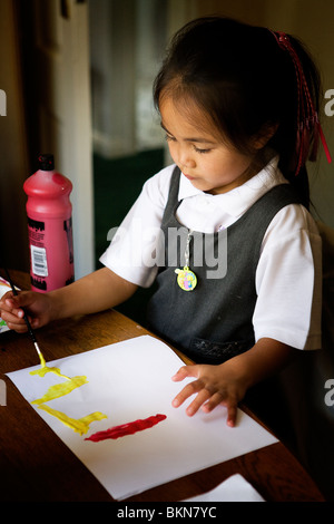 Young six year old half Thai girl is concentrating on painting a picture Stock Photo