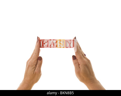 Woman holding children's blocks that spell 'EASY' Stock Photo