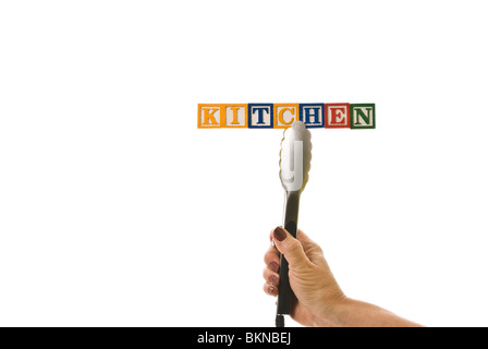 Woman with tongs holding children's blocks that spell 'KITCHEN' Stock Photo